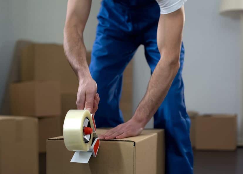 Packing and Unpacking: A man holding packaging tape sealing a box